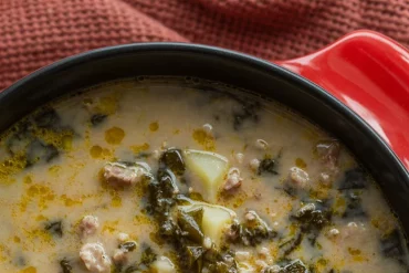 Warm up with a bowl of this rustic Tuscan Sausage & Potato Soup—a hearty slow cooker meal made with savory sausage, creamy cannellini beans, tender potatoes, and fresh kale. Perfect for cozy nights and family dinners! Just add crusty bread and you're set. #SlowCookerSoup #TuscanSoup #ComfortFood #FallRecipes #HeartySoup