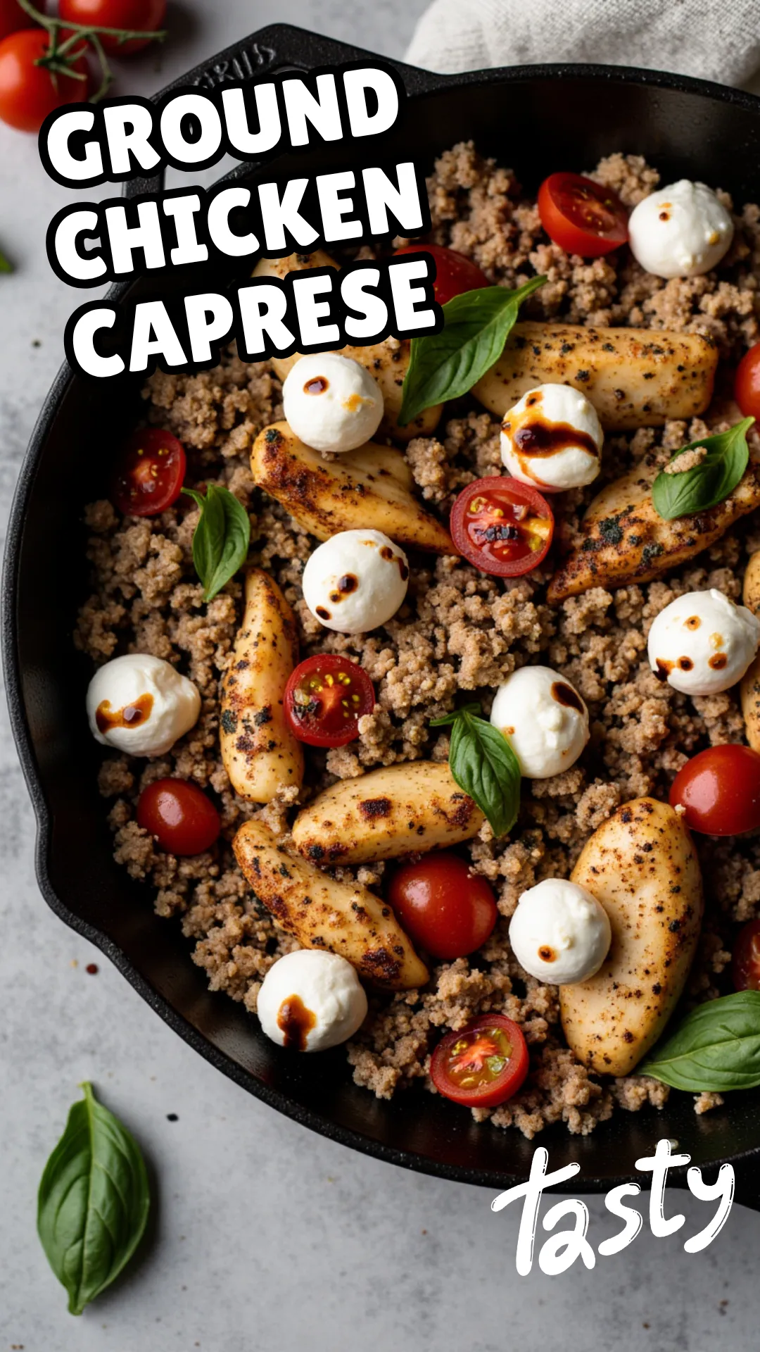 Skillet of browned ground chicken mixed with burst cherry tomatoes, melted mozzarella pearls, and fresh basil, finished with a drizzle of balsamic glaze, rustic styling
