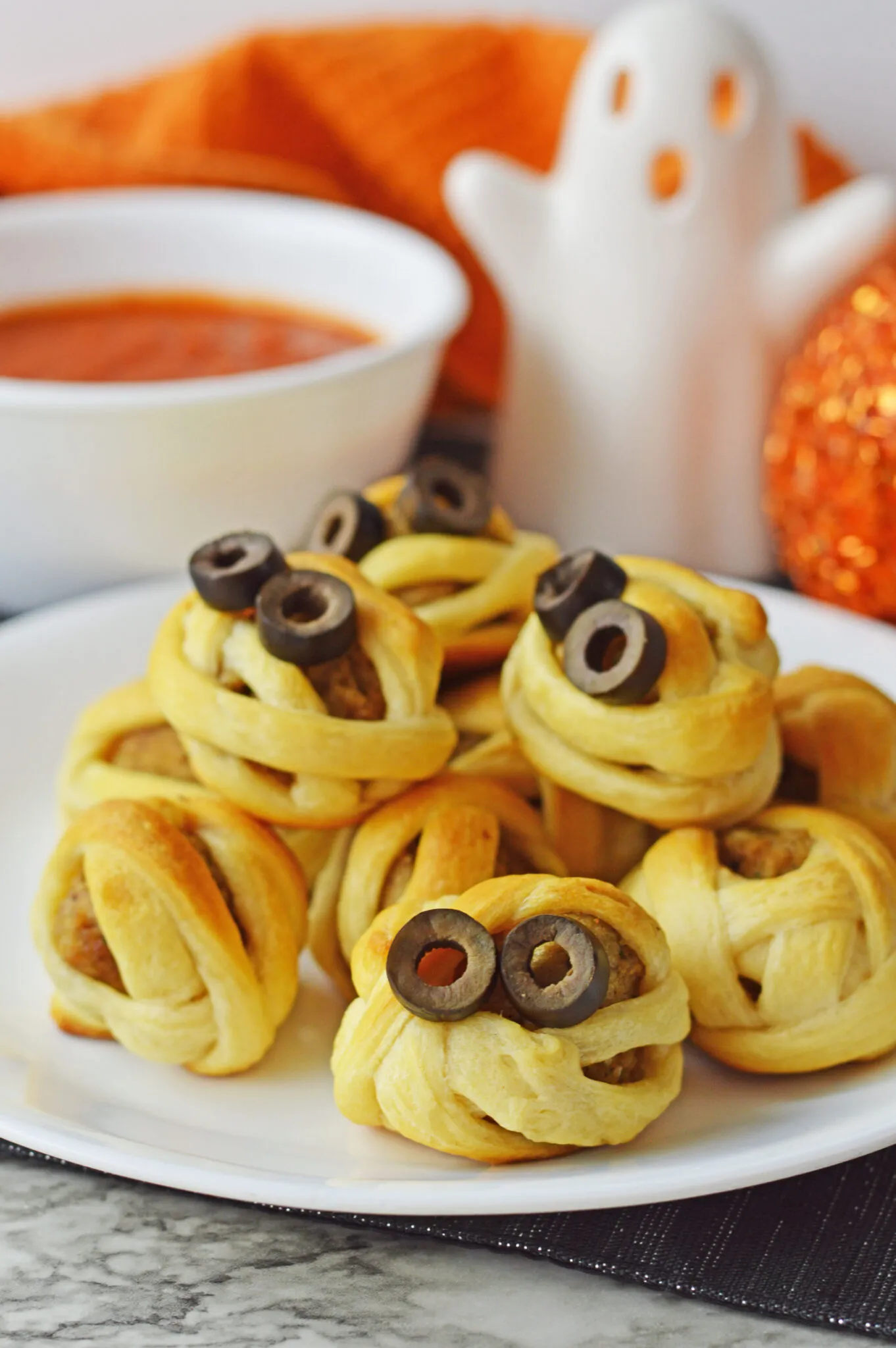 These spooky little meatballs wrapped in crescent roll "bandages" are almost too cute to eat—almost! Topped with sliced olive eyes and served with a side of marinara, they're a fun and easy party appetizer.